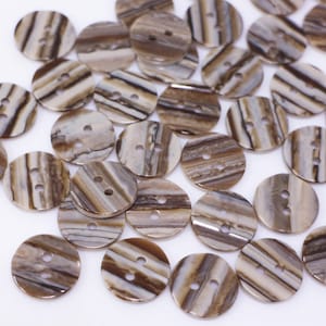 May include: A collection of brown and white striped buttons with two holes each. The buttons are made of a natural material, possibly shell or wood.