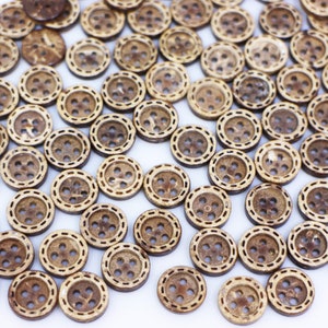 May include: A collection of brown coconut shell buttons with a decorative stitched edge. The buttons are arranged in a random pattern on a white background.