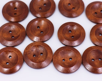 May include: Twelve brown wooden buttons with two holes each. The buttons are round and have a slightly raised edge.