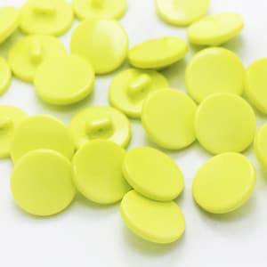 May include: A group of bright yellow plastic buttons, scattered on a white surface.