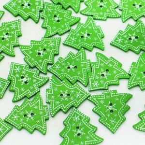 May include: A collection of green wooden Christmas tree buttons with white snowflake designs. The buttons are ideal for crafting and decorating.
