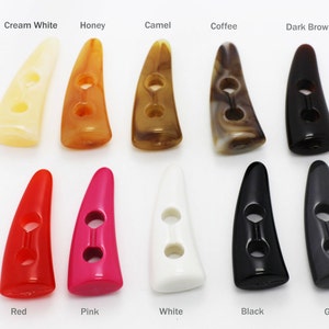 May include: Assortment of 10 two-hole horn buttons in various colors, including cream white, honey, camel, coffee, dark brown, red, pink, white, black, and grey.