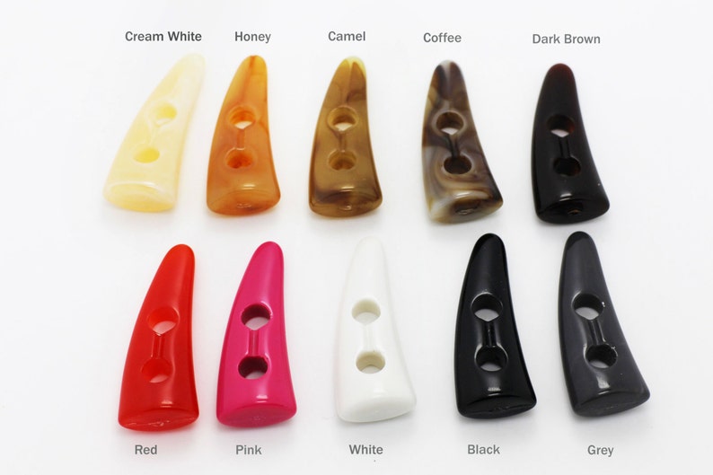 May include: Assortment of 10 two-hole horn buttons in various colors, including cream white, honey, camel, coffee, dark brown, red, pink, white, black, and grey.