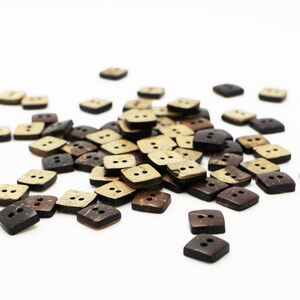 K&ouml;nnte beinhalten: Ein Haufen brauner und beiger quadratischer Kokosnuss-Kn&ouml;pfe mit jeweils zwei L&ouml;chern.