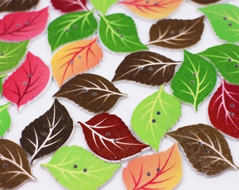 May include: Assortment of wooden leaf-shaped buttons in various colors, including green, brown, red, orange, and pink. The buttons have a natural wood grain texture and are decorated with painted details.