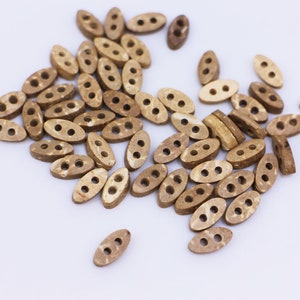 May include: A pile of brown wooden buttons with two holes each. The buttons are oval shaped and have a natural wood grain pattern.
