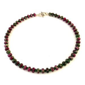 Pode incluir: Um bracelete de pedras preciosas verdes e rosa com um fecho de prata.