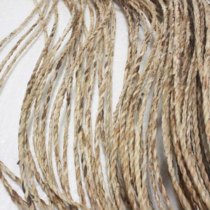 May include: A close-up of a bundle of natural fiber rope. The rope is made of a light brown material and has a slightly rough texture.
