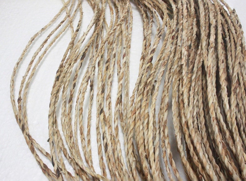 May include: A close-up of a bundle of natural fiber rope. The rope is made of a light brown material and has a slightly rough texture.