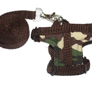 May include: A brown camouflage patterned pet harness with a brown leash and a silver clip.