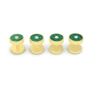 Op de afbeelding: Set van vier gouden manchetknopen met groene malachietstenen bovenkant en een enkele diamant accent in het midden van elke steen.