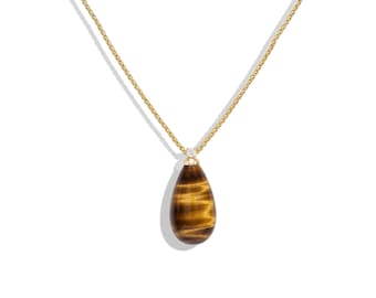 May include: A gold chain necklace featuring a teardrop-shaped tiger's eye pendant. The pendant is capped with a small gold setting that holds a single, tiny, clear round gemstone at the top, connecting the stone to the delicate gold chain.