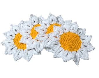 May include: Three crocheted sunflower coasters in white and yellow. The coasters are arranged in a semi-circle.