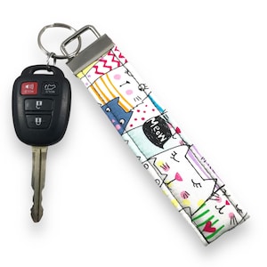 May include: White key chain with a colorful pattern of cats and the word "Meow".