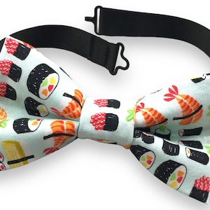 Könnte beinhalten: Ein hellblauer Fliege mit einem Sushi-Muster. Die Fliege hat ein verstellbares schwarzes Band.