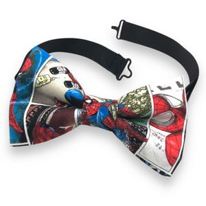 Puede incluir: Una pajarita con diseño de cómic que presenta ilustraciones de Spider-Man. La pajarita tiene una correa negra ajustable. La tela muestra paneles de Spider-Man en acción, con colores rojo, azul y blanco. Forma clásica.