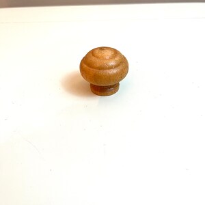 May include: A wooden knob with a rounded top and a smooth, light brown finish.
