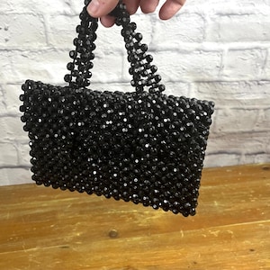 May include: A small black beaded handbag with a top handle.