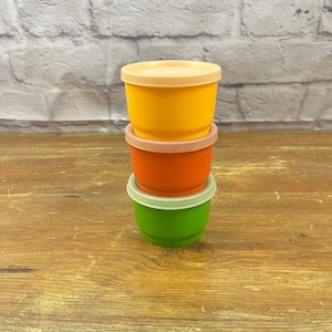 Può includere: Tre contenitori di plastica impilabili con coperchi. Il contenitore superiore è giallo, il contenitore intermedio è arancione e il contenitore inferiore è verde.