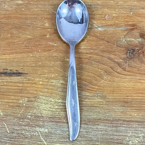 Op de afbeelding: Een roestvrijstalen lepel met een afgeronde kom en een slanke steel. De steel is versierd met stervormige uitsparingen. De lepel is ontworpen om te serveren en te eten.