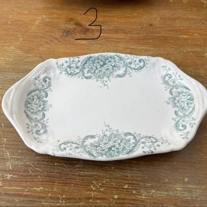 May include: White ceramic serving platter with a teal floral pattern. The platter is rectangular with curved edges. The floral design is concentrated around the edges and centre of the platter. The number 3 is written on the top.
