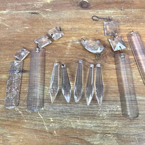 May include: A collection of clear glass crystal prisms, including teardrop, icicle, and square shapes. The prisms are strung together with wire and are perfect for adding sparkle to a chandelier or other home decor.