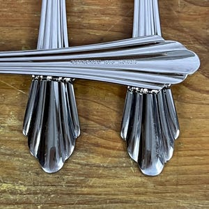 May include: Close-up of two silver forks with a decorative, scalloped design. The forks are marked "STAINLESS 18/8 KOREA".