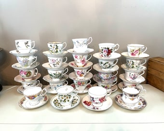 May include: A collection of 20 vintage teacups and saucers with floral patterns in various colors, including pink, blue, green, and yellow. The cups and saucers are stacked in groups of two or three.