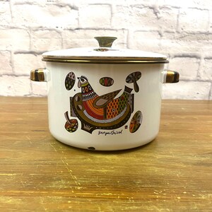 以下が含まれることがあります： 金色の縁取りと蓋が付いた白いエナメル製の鍋。鍋には、鳥とキノコのカラフルなイラストが描かれています。鍋には「ジョルジュ・ブリヤール」の署名があります。