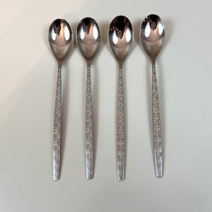 Puede incluir: Cuatro cucharas de plata con un patrón decorativo en el mango.