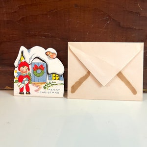 Cartolina di Natale dell'annata, ragazza sveglia che tiene il regalo Cartolina di buon Natale