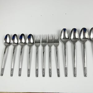 May include: A set of 10 silver-toned flatware pieces, including spoons and forks. The flatware has a decorative design on the handles.