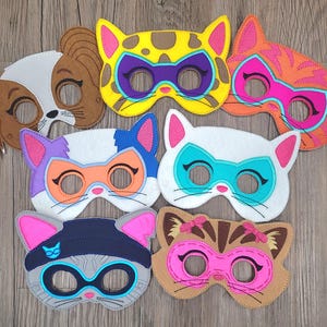 May include: A collection of seven felt animal masks featuring various designs including a brown and white dog, a yellow leopard, an orange tabby cat, a white cat with a blue mask, a grey cat with a beanie, and a brown cat with pink accents.