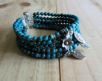 May include: A turquoise blue multi-strand bracelet with silver flower and leaf charms.