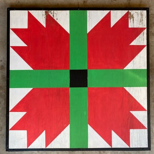 May include: A red, green, and black barn quilt with a geometric design. The quilt is made of wood and has a black frame.