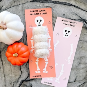 May include: Halloween-themed gift tags with the phrases "DONUT BE SCARED, HALLOWEEN IS SWEET" and "NO BONES ABOUT IT, YOU ARE SWEET." The tags feature skeleton illustrations and are paired with decorative pumpkins and donuts.