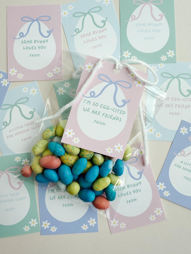 K&ouml;nnte beinhalten: Ein Set Ostergeschenkanh&auml;nger in Pastellfarben mit Blumenmustern. Die Anh&auml;nger zeigen verschiedene Botschaften, darunter "Some bunny loves you" und "I'm so egg-cited we are friends".