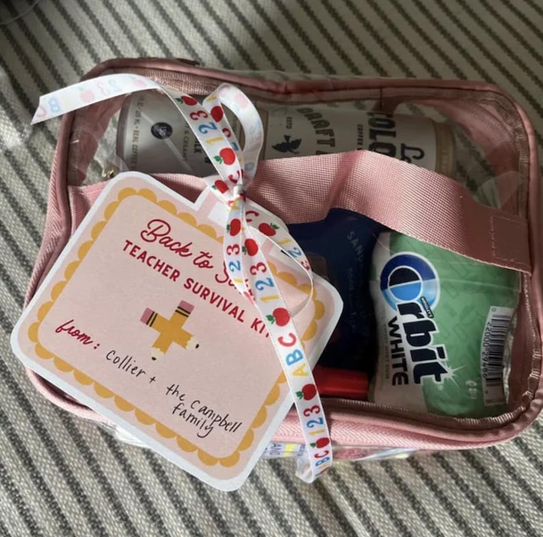 K&ouml;nnte beinhalten: Eine rosa, transparente Rei&szlig;verschlusstasche gef&uuml;llt mit verschiedenen Artikeln, darunter eine Kaffeekanne und Orbit-Kaugummi. Ein Geschenkanh&auml;nger mit dem Text "Back to School Teacher Survival Kit" ist mit einem Band befestigt.