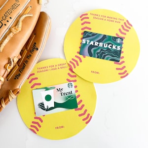 Può includere: Un guanto da baseball e due porta carte regalo gialli a forma di palline da baseball. I porta carte regalo hanno cuciture rosa e il testo "THANKS FOR MAKING THIS SEASON A HOME RUN" e "THANKS FOR A GREAT SEASON! I HAD A BALL!". Le carte regalo sono di Starbucks.