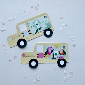 May include: Two yellow school bus-shaped gift cards with a green and white Starbucks gift card on the top card and a green and white Starbucks gift card with three cups of coffee on the bottom card. The text on the top card reads "My Treat" and the text on the bottom card reads "Sip Sip Hooray Happy First Day".