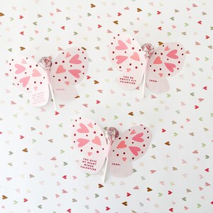 May include: Three pink butterfly-shaped Valentine's Day cards with lollipop sticks. Each card has a different message: "You have my heart flutter Valentine", "You're pretty fly Valentine", and "You give my heart wings Valentine".