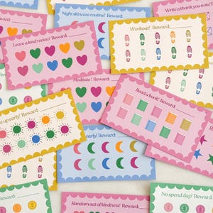 May include: A collection of colorful reward cards with scalloped edges. The cards feature various designs, including hearts, footprints, moons, and suns, with prompts like "Read a book! Reward:" and "Workout! Reward:". The cards are in shades of pink, blue, yellow, and green.