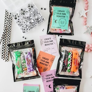 Puede incluir: Kits de manualidades con tem&aacute;tica de Halloween con el texto "Create Your Own Monster". Los kits incluyen plastilina, ojos saltones y pajitas decorativas. Empaquetados en bolsas negras con tarjetas coloridas con ilustraciones de monstruos.