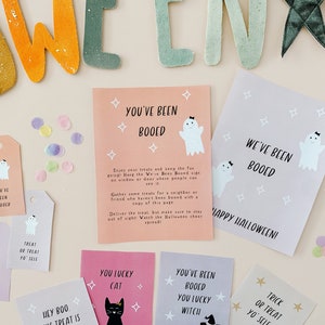 May include: A collection of Halloween-themed cards and tags with ghost illustrations and the phrase "You've Been Booed." The cards are in pink, purple, and gray, with confetti scattered around. The tags say "Treat or Treat Yo' Self."