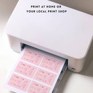 May include: A white printer printing sheets of pink labels. The labels have text and illustrations. The text on the image reads: "PRINT AT HOME OR YOUR LOCAL PRINT SHOP."