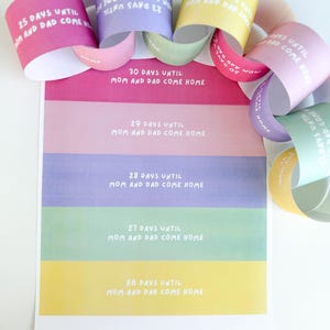 Könnte beinhalten: Eine bunte Countdown-Kette mit Papierringen in Rosa, Lila, Gelb und Grün. Jeder Ring hat eine Nummer und den Text "Tage bis Mama und Papa nach Hause kommen".