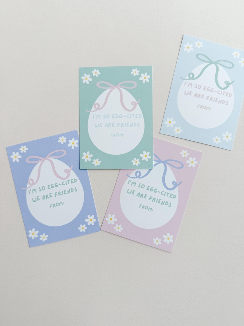 K&ouml;nnte beinhalten: Vier pastellfarbene Ostergeschenkanh&auml;nger mit einem wei&szlig;en Ei-Design und einem rosa Band. Jeder Anh&auml;nger hat den Text "I'm so egg-cited we are friends" und einen Platz zum Schreiben von "from".