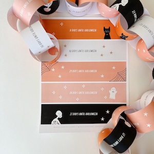 May include: A printable Halloween countdown chain with orange, black, and white paper circles. Each circle has a different Halloween character and the number of days until Halloween. The text on the chain reads "31 days until Halloween", "30 days until Halloween", "29 days until Halloween", "28 days until Halloween", "27 days until Halloween", and "20 days until Halloween".