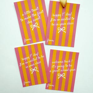 Pu&ograve; includere: Quattro etichette regalo rettangolari con strisce verticali rosa e arancioni. Ogni etichetta ha testo bianco e una grafica a fiocco. Le etichette recitano: "a little treat to make the first day sweet", "happy 1st day!"