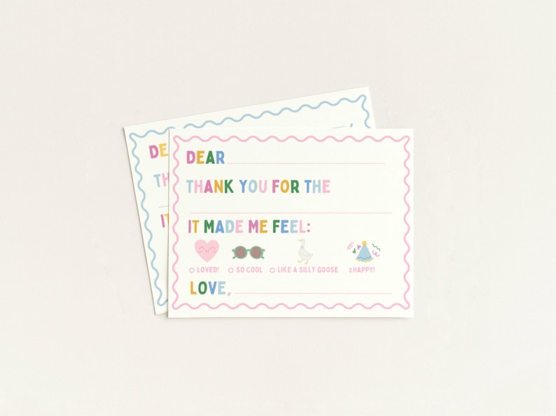 May include: Two white fill-in thank you cards with a wavy border. The cards have text in rainbow colors that reads "DEAR THANK YOU FOR THE IT MADE ME FEEL:" with icons and fill-in options. The cards are on a white background.